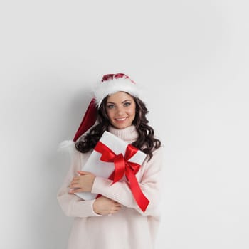 Young woman in Santa hat hug her Christmas gift