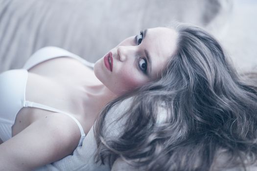 Portrait of beautiful young woman in lingerie on sofa