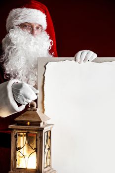 Santa Claus with vintage glowing lantern and big blank card