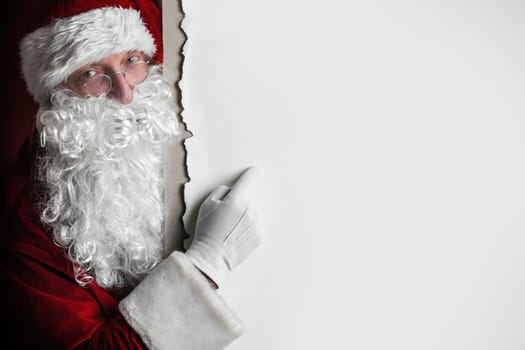 Santa Claus pointing at copy space at big blank card