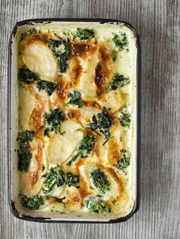 close up of rustic golden spinach potato gratin dauphinois