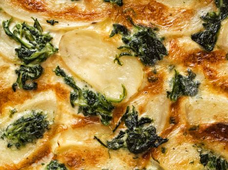 close up of rustic golden spinach potato gratin dauphinois food background