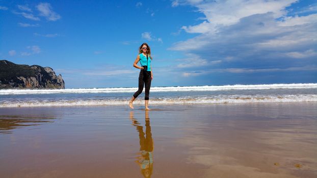 girl with camera walking on the water on the beach