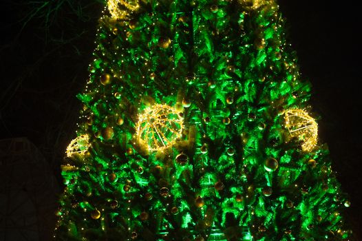 Green Christmas tree with garlands in winter park