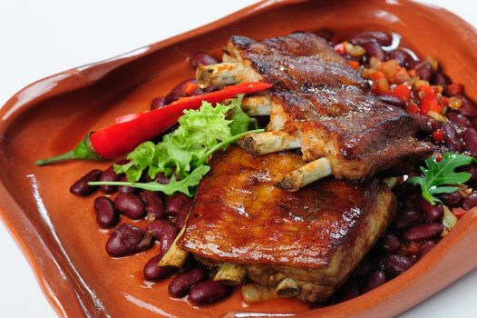 two pieces of grilled pork spare ribs with herbs at broun plate
