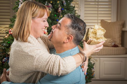 Happy Young Mixed Race Couple with Present Near Christmas Tree.