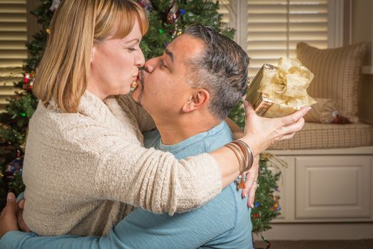 Happy Young Mixed Race Couple with Present Near Christmas Tree.