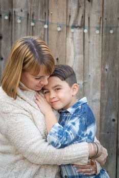 Loving Mother and Mixed Race Son Hug Near Fence.