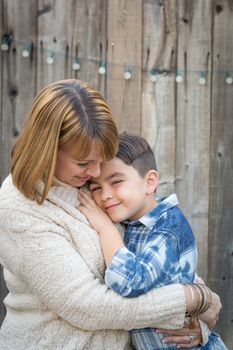 Loving Mother and Mixed Race Son Hug Near Fence.