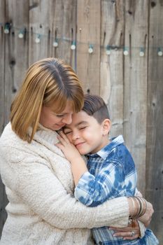 Loving Mother and Mixed Race Son Hug Near Fence.
