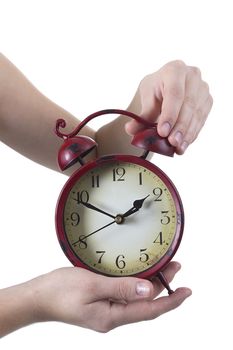 Female hands with the old red alarm clock