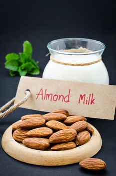 Almond with almond milk in glass with almond milk tag on black background.