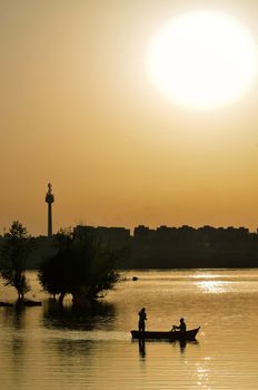 silhouette of fishermen with and orange sun on Danube river