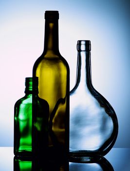 Arrangement of Empty Wine and Cognac Colored Bottles with Reflection on Glass and Shadow Toned Backlight
