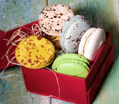 Assorted Traditional Colorful Macarons in Red Gift Box closeup on Cracked Wooden background in Shadow