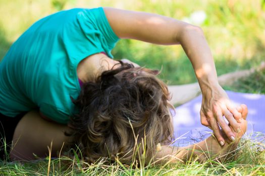 A woman sitting at a head to knee yoga posture with her hand on her feet