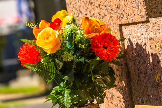 Flowers on a headstones in a cemetery with hundreds of tombstones in the background