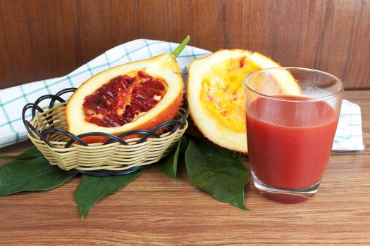 Baby Jack fruit and juice (Or Cochinchin Gourd, Spiny Bitter Gourd, Sweet Gourd, Momordica cochinchinensis, Momordica cochinchinensis (Lour) Spreng.) on wood table