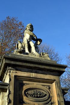 Sculpture of a little boy with a falcon and a book on a column