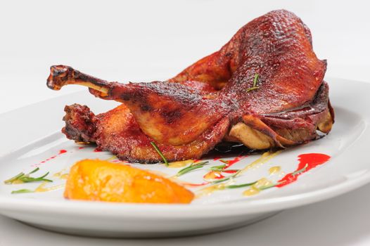 Roast half of duck with caramelized lemon on white plate