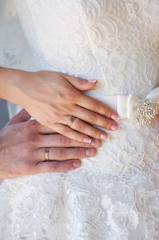 hands of the bride and the groom with the bride's dress rings.