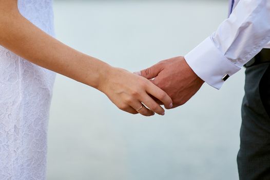 bride and groom holding hands in wedding day closeup.