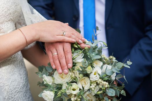 hands of the bride and groom at a wedding bouquet.