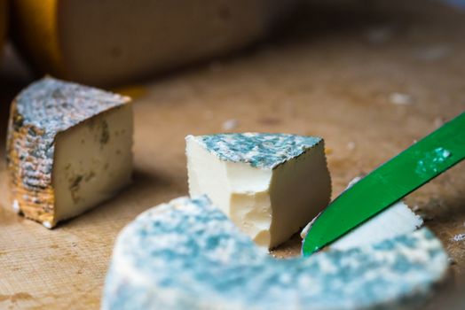 a pieces of cheese with blue mold is cut with a knife