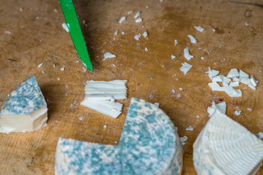 a pieces of cheese with blue mold is cut with a knife