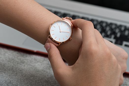 Girl's hand with wrist watch in front of desk with laptop computer