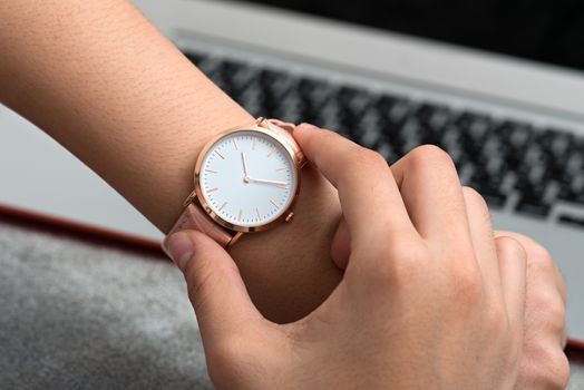 Girl's hand with wrist watch in front of desk with notebook computer