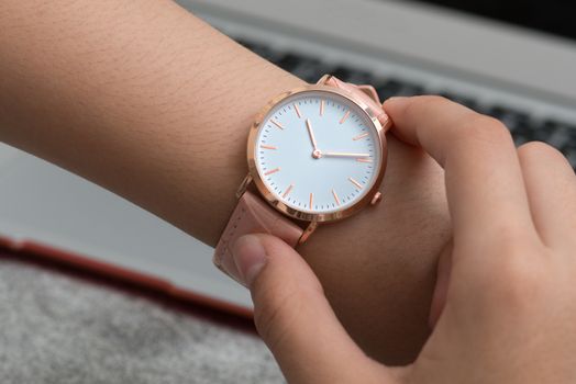 Girl's hand with wrist watch in front of desk with notebook computer