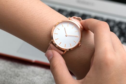 Girl's hand with wrist watch in front of desk with notebook computer
