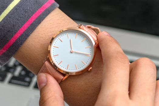 Wrist watch on girl's hand in front of a laptop computer