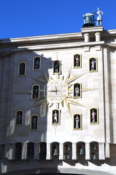 Clock face on a sun-shaped facade with figurines and a bell ringer