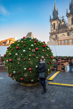 Beautiful middle age woman in Prague Old Town square, with tree decorated as christmas ball