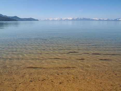 Scenic view of beautiful Lake Tahoe in Spring, landscape of the United States of America, clear water, nice sky, stone island, tree, fresh air and snow mountains