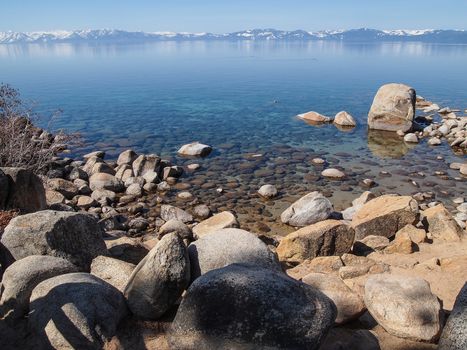 Scenic view of beautiful Lake Tahoe in Spring, landscape of the United States of America, clear water, nice sky, stone island, tree, fresh air and snow mountains