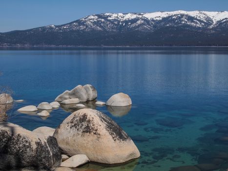 Scenic view of beautiful Lake Tahoe in Spring, landscape of the United States of America, clear water, nice sky, stone island, tree, fresh air and snow mountains