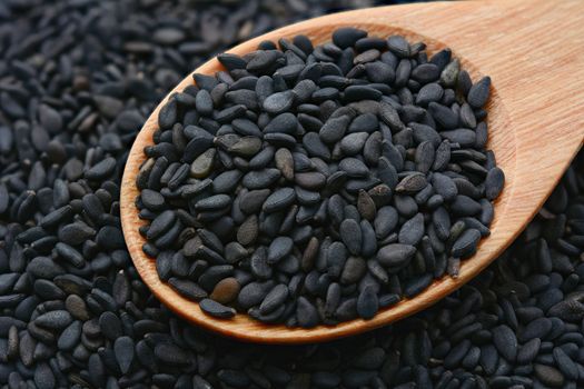 Closeup of black sesame seeds in wooden spoon