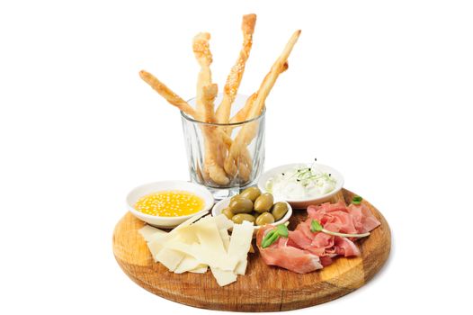 Assorted cheeses, wallnuts, prosciutto, green olives and other snacks served at wooden board