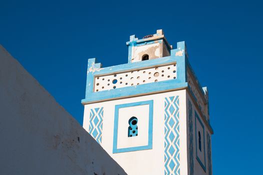 Blue and white architecture, typical for the area by the Atlantic ocean. Minaret of a mosque with a blue bright sky in the background. Sidi Ifni, Morocco.