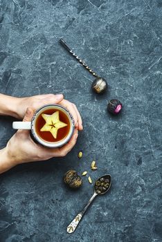 With warming mug of tea in hand on blue slate background