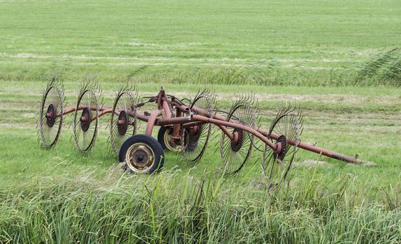 Old red agricultural machinery on green land 
