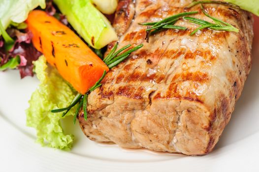 Grilled pork meat and vegetables on white plate with mustard sauce