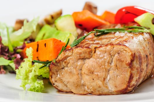 Grilled pork meat and vegetables on white plate with mustard sauce
