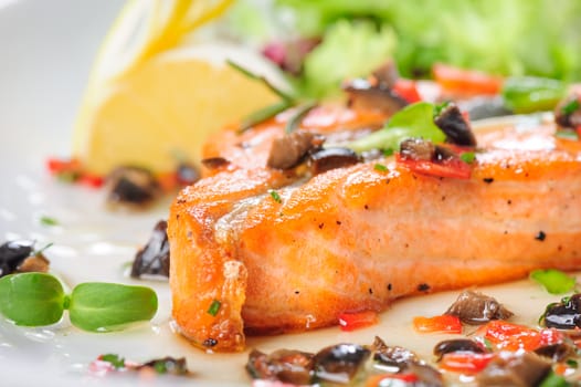 Roasted salmon steak with rosemary, lemon and lettuce, on white plate. Selective focus.