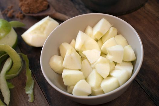 Preparing the ingredients for apple sauce with diced fresh green cooking apples in a bowl with ground aromatic cinnamon spice for flavoring