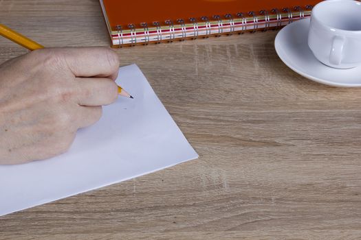 Hand of man with a pencil behind his desk