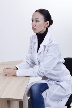 Young female doctor at the table on a white background